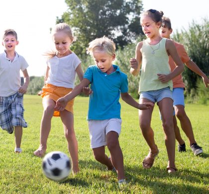 active kids having fun and kicking football outdoors  on summer day